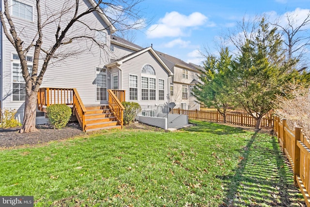 rear view of property featuring a deck, a yard, stairway, and a fenced backyard