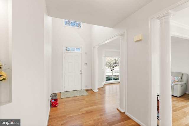 foyer with baseboards, wood finished floors, and ornate columns