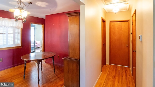 hallway featuring a notable chandelier, baseboards, and wood finished floors