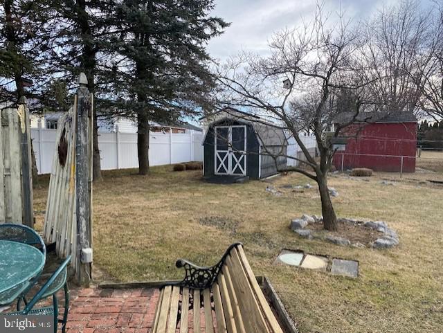 view of yard featuring an outbuilding, a fenced backyard, and a shed