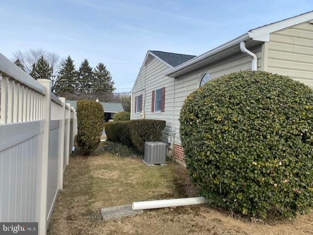 view of side of home with central air condition unit and fence