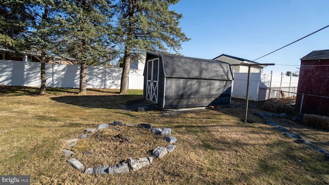 view of yard featuring an outdoor structure, a fenced backyard, and a shed