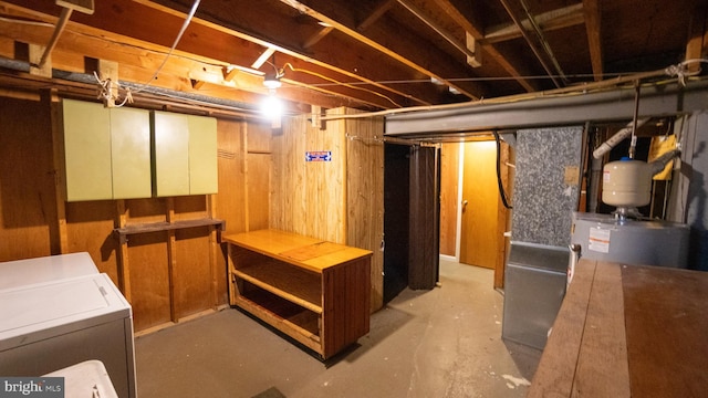 unfinished basement featuring gas water heater, washer / clothes dryer, and wooden walls