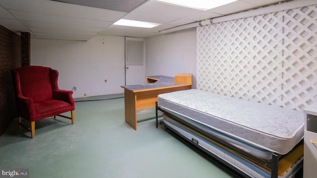 bedroom with concrete flooring and a paneled ceiling