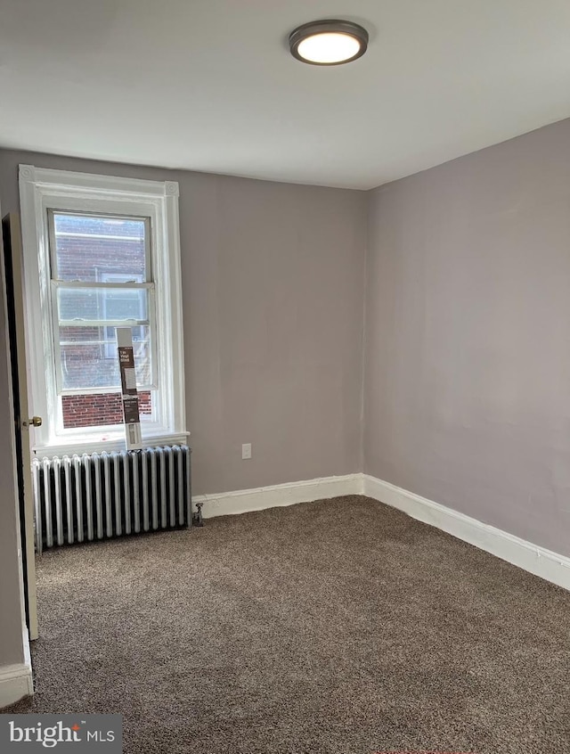 empty room with radiator heating unit, carpet flooring, and baseboards