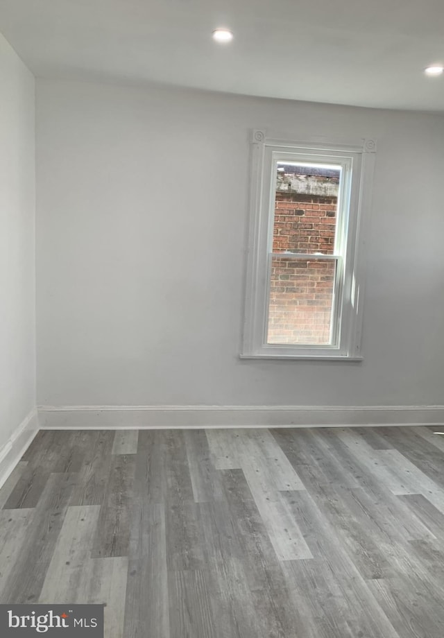 unfurnished room featuring baseboards, wood finished floors, and recessed lighting