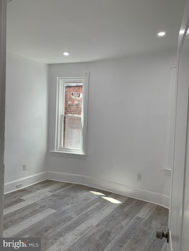 empty room with recessed lighting, baseboards, and wood finished floors