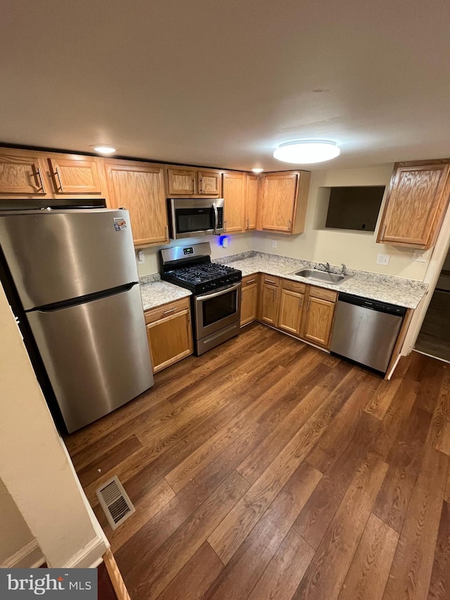 kitchen featuring sink, dark wood-type flooring, appliances with stainless steel finishes, and light stone countertops