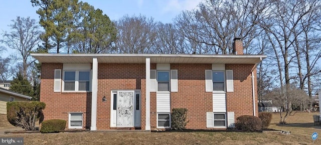 bi-level home featuring a front yard, brick siding, and a chimney