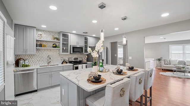 kitchen with a sink, appliances with stainless steel finishes, a breakfast bar, and gray cabinets