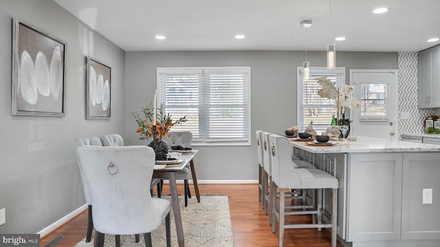 dining room with light wood-style flooring, baseboards, and a wealth of natural light