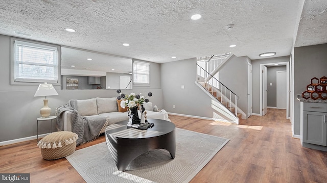 living area featuring baseboards, light wood-style flooring, recessed lighting, stairs, and a textured ceiling