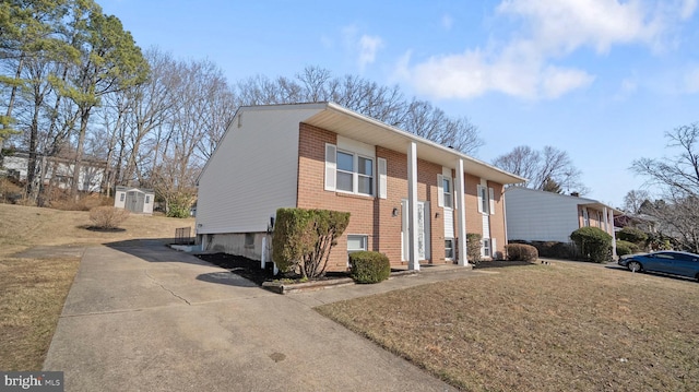 view of front facade with an outbuilding, a storage unit, brick siding, and a front lawn