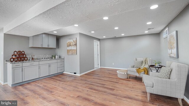 sitting room with recessed lighting, light wood-style floors, baseboards, and a textured ceiling