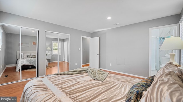 bedroom with baseboards, ensuite bath, light wood-style flooring, recessed lighting, and multiple closets