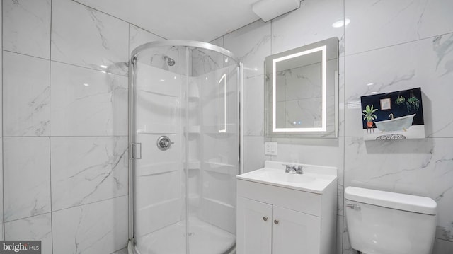 bathroom featuring vanity, a shower stall, toilet, and tile walls