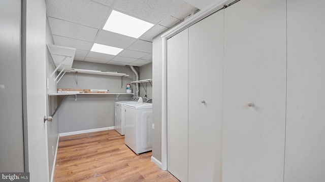 laundry room with light wood-style flooring, baseboards, washing machine and dryer, and laundry area