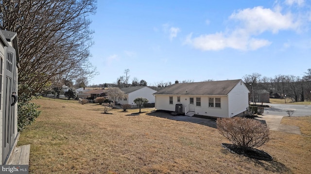 rear view of house featuring entry steps and a lawn