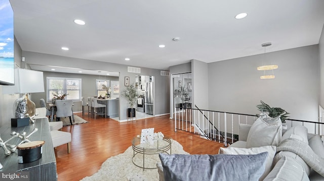 living area with recessed lighting, visible vents, baseboards, and wood finished floors