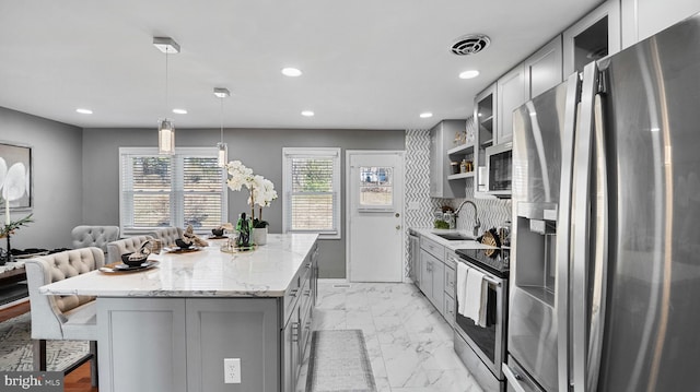 kitchen with visible vents, gray cabinetry, a sink, a center island, and appliances with stainless steel finishes