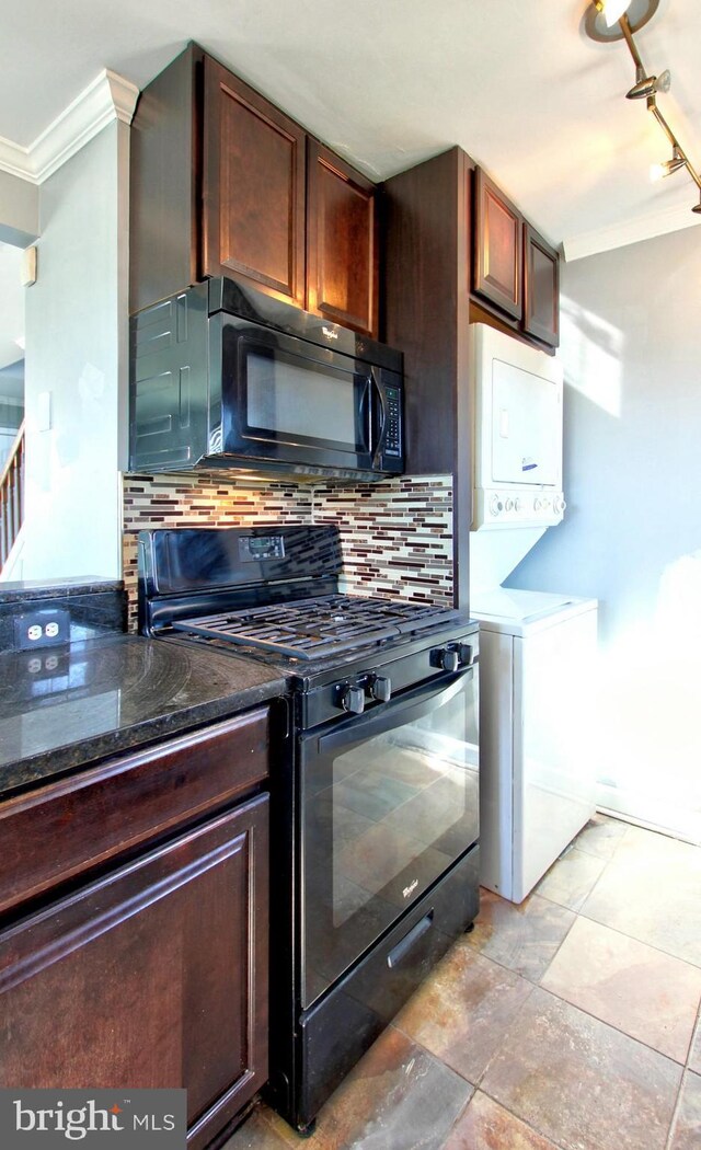 kitchen with stacked washer / dryer, dark stone countertops, decorative backsplash, and black appliances