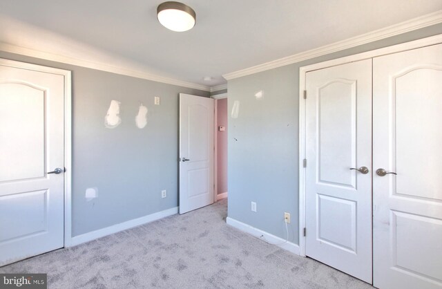 unfurnished bedroom featuring light colored carpet, ornamental molding, and a closet