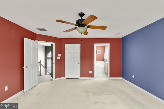 unfurnished bedroom featuring ensuite bathroom, light colored carpet, and ceiling fan