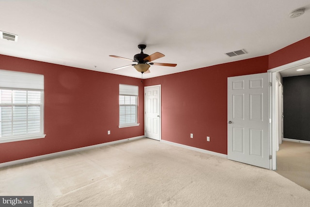 spare room with ceiling fan, plenty of natural light, and light carpet