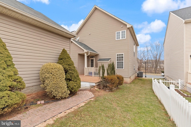 back of property with a lawn, central air condition unit, and a deck