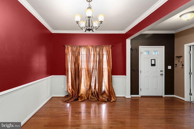 entryway featuring hardwood / wood-style floors, ornamental molding, and a chandelier