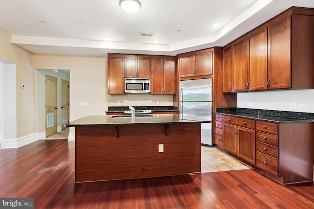 kitchen with wood finished floors, visible vents, appliances with stainless steel finishes, and dark stone counters