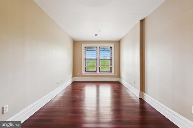 unfurnished room with baseboards and dark wood-style flooring
