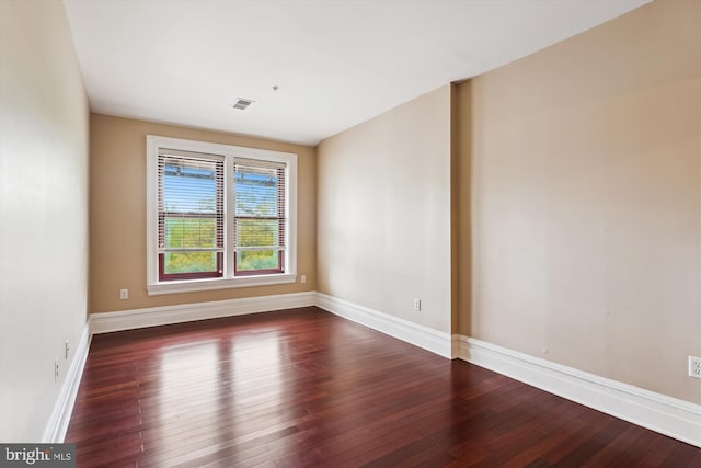 spare room with baseboards, visible vents, and dark wood-type flooring