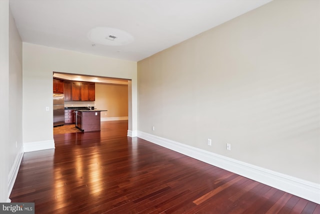 unfurnished living room with baseboards and dark wood finished floors