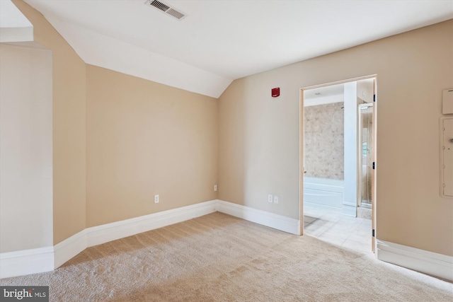 carpeted empty room featuring baseboards, vaulted ceiling, and visible vents