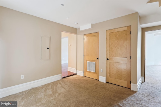 unfurnished bedroom featuring electric panel, baseboards, visible vents, two closets, and carpet floors