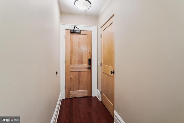 hallway featuring baseboards and dark wood-style flooring
