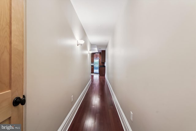 hallway featuring baseboards and dark wood-style flooring