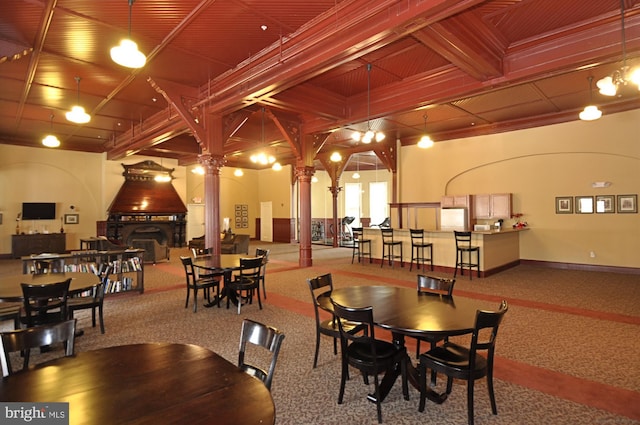 dining room with beamed ceiling, carpet floors, and ornate columns