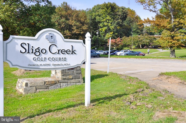community / neighborhood sign featuring uncovered parking and a yard