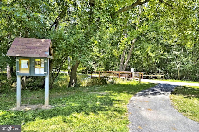 view of property's community featuring fence, a view of trees, and a yard