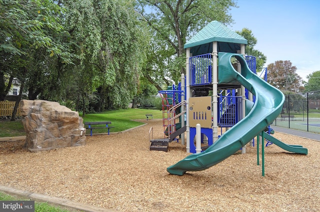community play area featuring fence and a yard