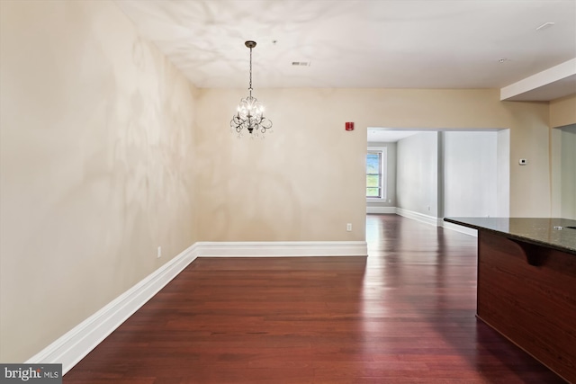 unfurnished dining area with a chandelier, baseboards, visible vents, and dark wood-style floors