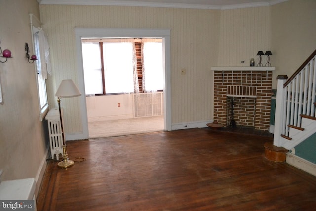 unfurnished living room featuring a tiled fireplace, wood-type flooring, ornamental molding, and radiator