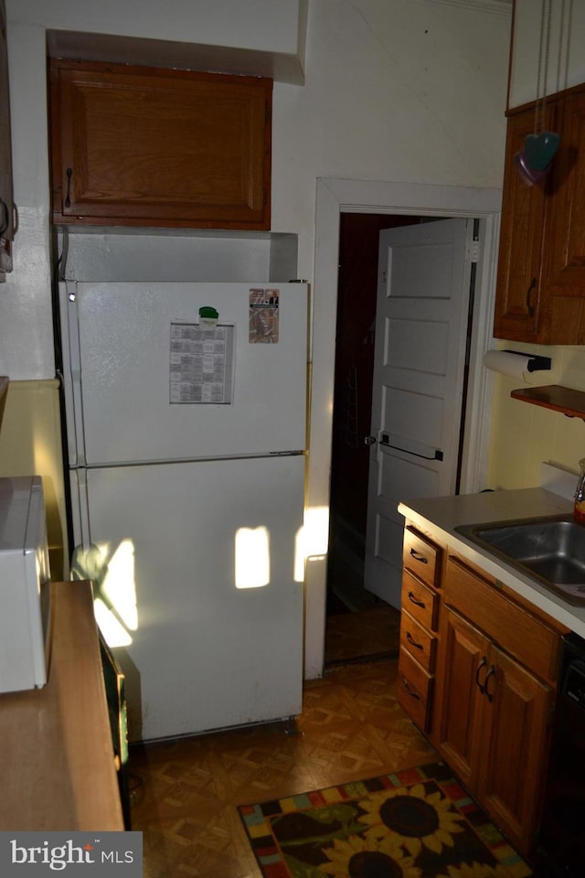 kitchen with sink, dark parquet floors, dishwasher, and white refrigerator