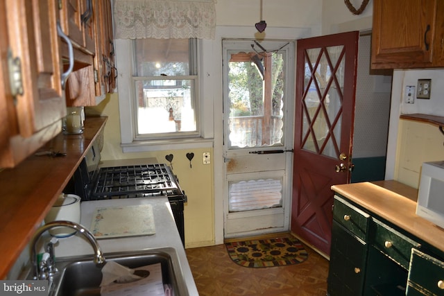 kitchen with gas stove, dark parquet flooring, and sink