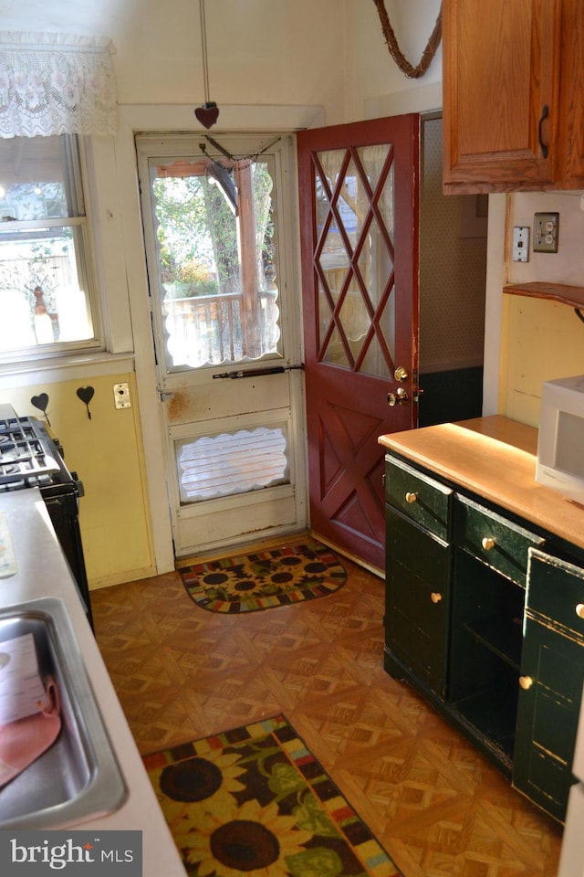 kitchen with black stove, parquet flooring, and sink