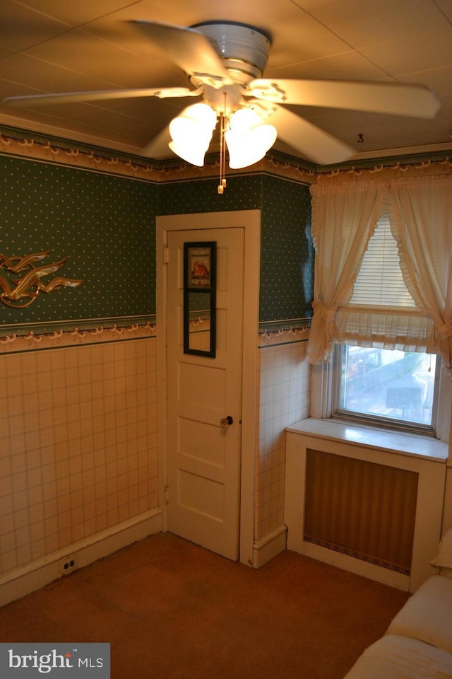 interior space featuring ceiling fan, radiator, and tile walls