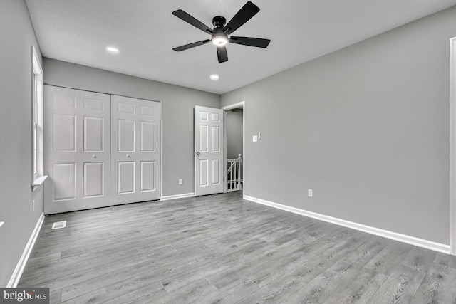 unfurnished bedroom featuring ceiling fan, a closet, and light hardwood / wood-style flooring