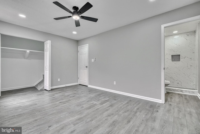 unfurnished bedroom featuring ceiling fan, ensuite bath, light wood-type flooring, and a closet